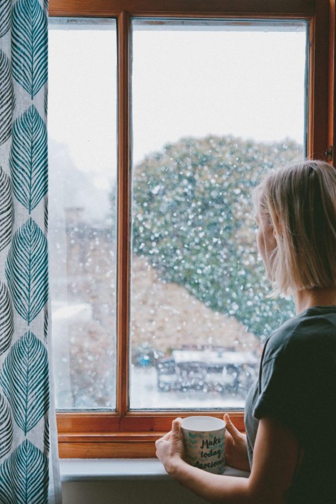 woman looking out window at garden