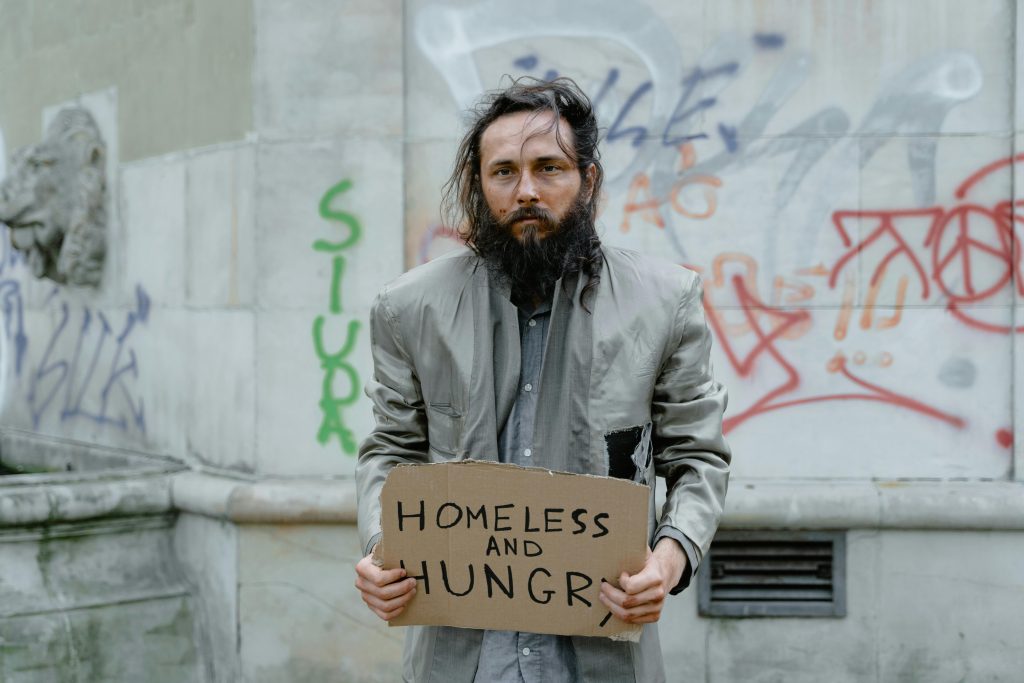 Homeless man holding homeless and hungry sign